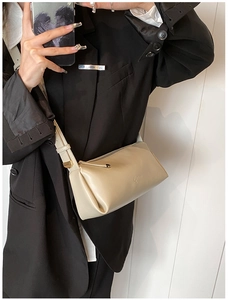 Detail of a beige PU leather crossbody bag with smooth texture and gold metal buckle
