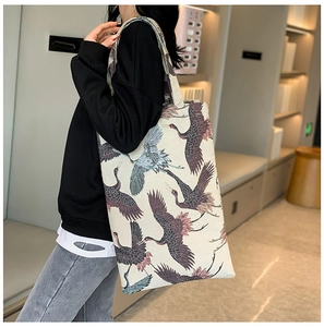 Detail of canvas tote bag with crane print shown on shoulder in a soft home setting