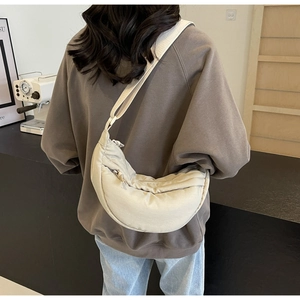 Detailed back view of a beige quilted crescent crossbody bag worn by a model