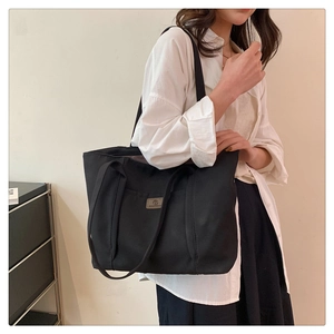 Detailed shot of large black canvas tote bag showing capacity and wide shoulder straps