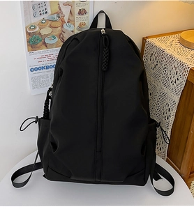 Close-up of black nylon backpack featuring vertical zipper pocket and functional side drawstring