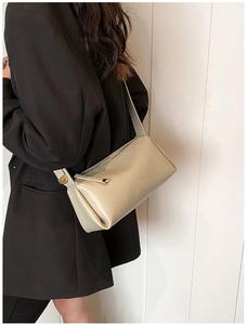 Close-up of beige minimalist PU leather crossbody bag with long zipper detail on model
