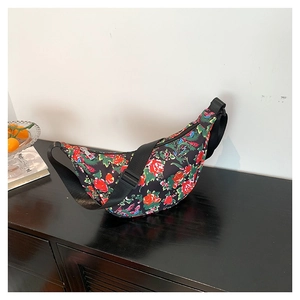 Floral print crescent crossbody bag with adjustable wide strap shown in home setting