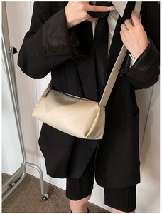 Detail of minimalist beige PU crossbody bag worn with professional business attire