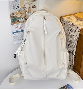 Detail of white nylon backpack with vertical zipper pocket and woven rope pull on a desk