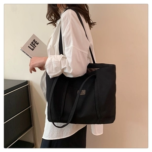 Detail showing the spacious black canvas tote bag with a small woven label patch