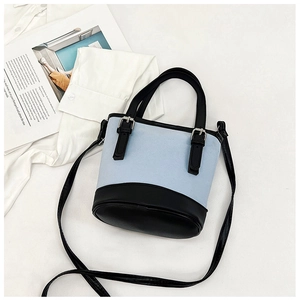 Flat lay of a light blue and black contrast bucket bag with a magazine and white shirt