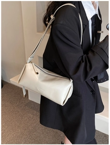 Close-up of beige PU leather crossbody bag with LUKADI logo on a model in a black blazer