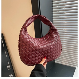 Detailed view of the dark red woven leather handbag with a minimalist hobo design