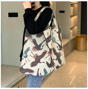 Detailed view of cream canvas tote bag featuring traditional crane prints on a model