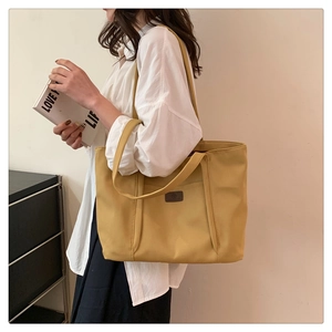 Detail view of the large capacity yellow nylon tote bag with wide shoulder straps