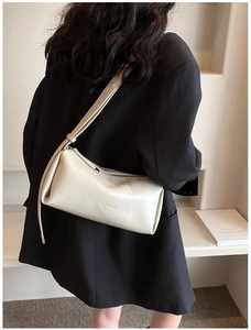 Detail of a light beige PU leather crossbody bag with LUKADI logo on black blazer