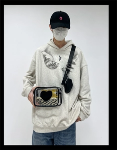 Détail du sac bandoulière en PVC transparent avec écusson coeur noir et porte-monnaie rond