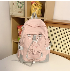 Detailed view of pink nylon backpack with grey straps and a cute star plush keychain