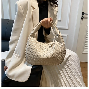 Detail view of beige woven PU leather handbag with Intrecciato pattern and crescent shape