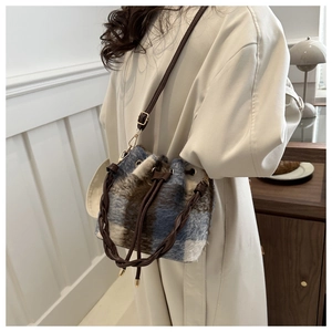 Detail view of the plush checkered bucket bag with drawstring and woven leather handle