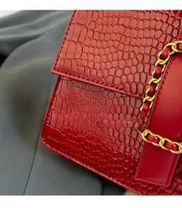 Close-up of red crocodile embossed PU leather handbag with elegant gold chain detail
