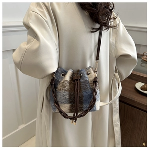 Detail of blue and beige plaid faux fur bucket bag with brown leather drawstring closure