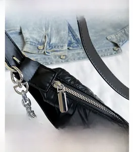 Close-up of silver metal zipper and quilted PU leather on the black crossbody shoulder bag