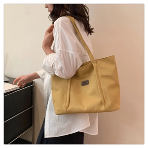 Detail view of mustard yellow canvas tote bag showing large capacity and shoulder straps