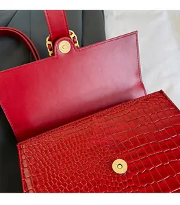 Detail of red crocodile texture PU leather handbag featuring a secure gold circular magnetic snap