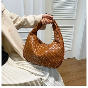Detailed macro view of woven leather texture and knot handle on brown PU hobo bag
