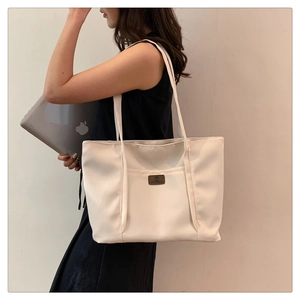 Close-up of white canvas tote bag with spacious interior showing a laptop for size