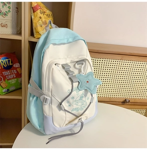 Detail of nylon backpack featuring astronaut cartoon illustrations and star pendant charm