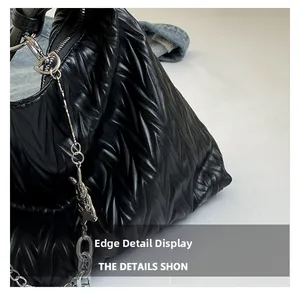 Detailed macro of black pleated PU shoulder bag with silver chain and rabbit charm