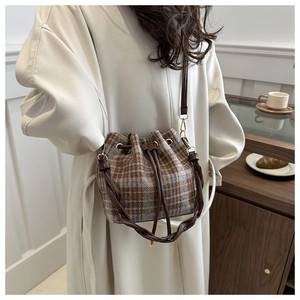 Detail of checkered bucket bag with brown leather drawstring and crossbody strap
