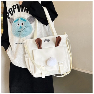 Detail view of white nylon tote bag featuring cute rabbit ears and plush pom pom ball
