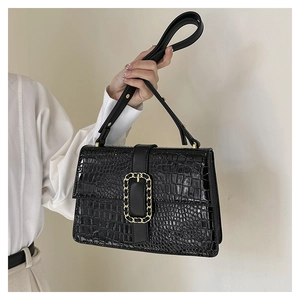 Detail showing black faux crocodile leather texture and golden metal chain buckle decoration