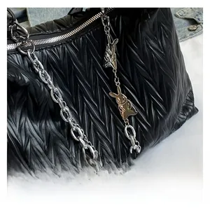 Detail of black matelassé crossbody bag with silver chunky chain and rabbit charms