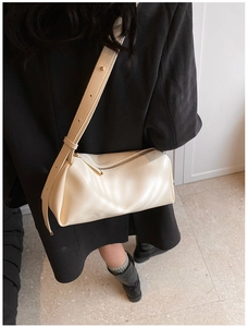Detailed close-up of a cream PU leather crossbody bag with debossed logo and adjustable strap