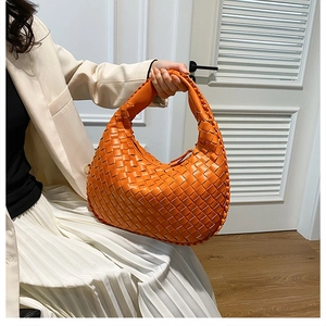Detail of orange woven PU leather hobo handbag with soft thick handle shown by model