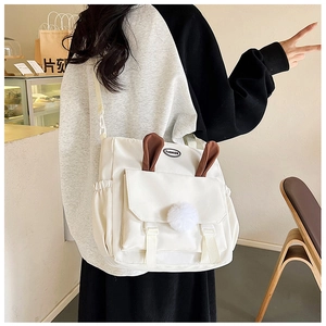 Detail of the cute rabbit ear flap and plush pompom on this white nylon crossbody bag