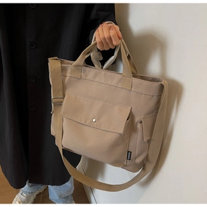 Detail of khaki canvas tote bag showing silver buckle pocket and durable fabric texture