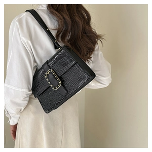 Detail of black crocodile texture shoulder bag with gold chain buckle on model