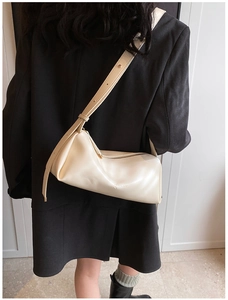 Chic cream white leather cylinder bag with adjustable strap worn on model shoulder