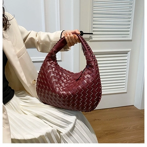 Detailed side view of deep red woven PU leather hobo handbag held by a fashion model