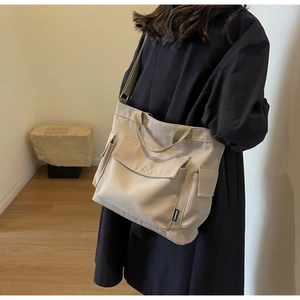 Detail of minimalist beige canvas tote bag showing side pocket and adjustable strap