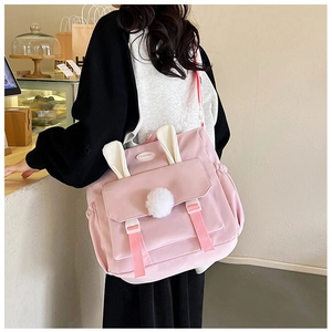 Detailed view of pink nylon backpack with 3D rabbit ears and soft white pom-pom accessory