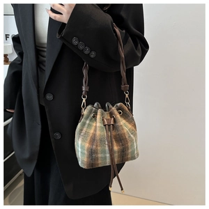 Detailed view of checkered wool bucket bag featuring leather drawstrings and woven handle