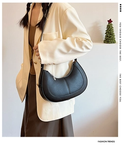 Detail of black pebbled leather hobo crossbody bag with adjustable strap worn by model