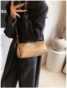 Close-up of a light brown cylindrical PU leather bag with metal zipper and thin strap