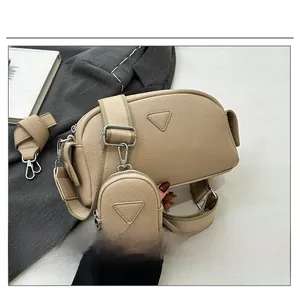 Detailed close-up of khaki pebbled leather crossbody bag with triangular emblem design
