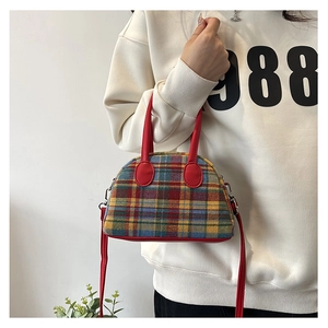 Detail of vintage colorful plaid fabric handbag with red leather handle and strap