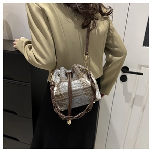Detailed close-up showing the wool plaid bucket bag texture and leather strap on a model