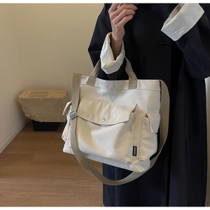 Detail view of cream canvas tote bag with functional pockets and adjustable shoulder strap