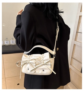 Detailed side view of beige pleated PU shoulder bag with decorative bows on a model